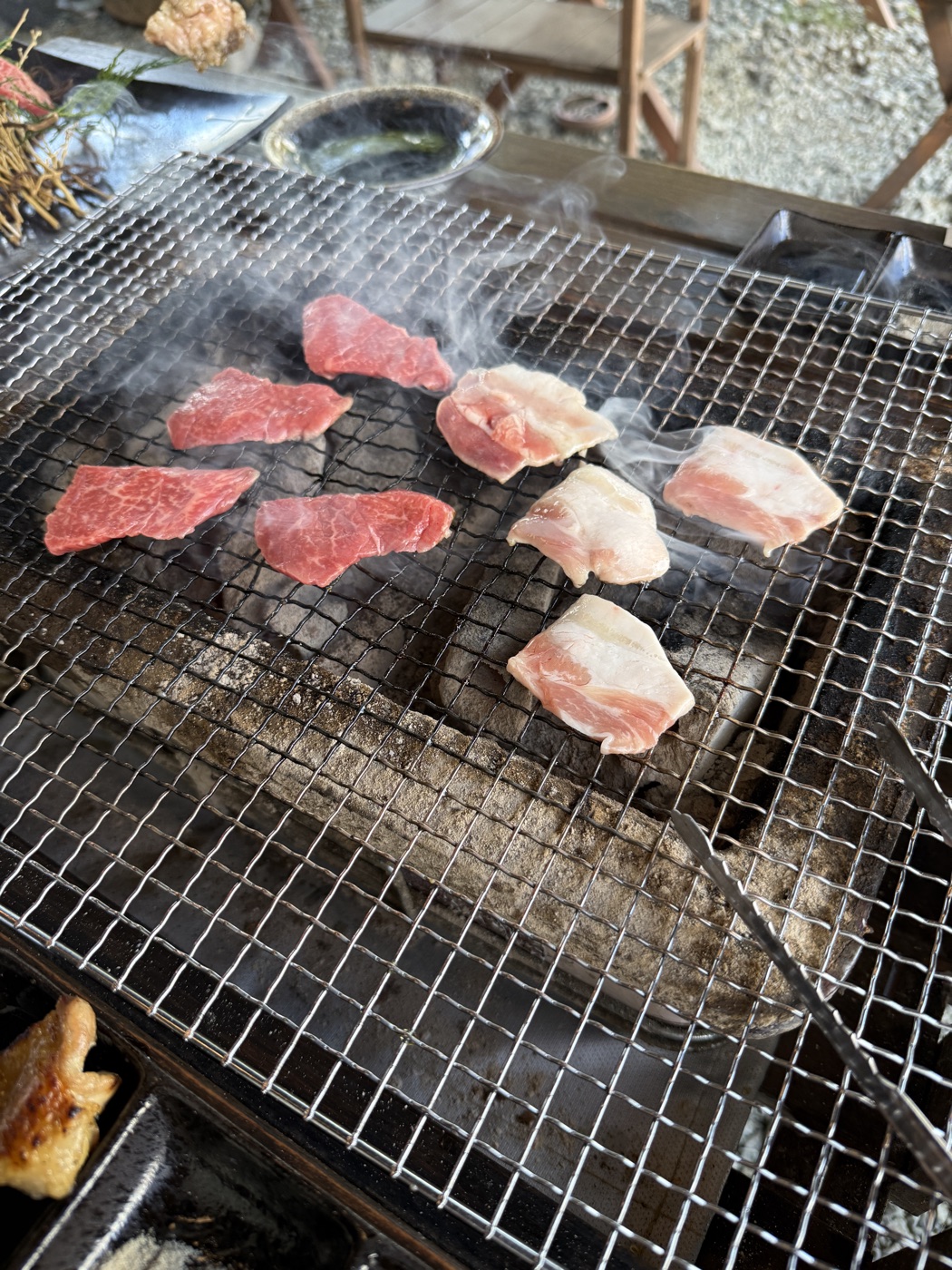 炭火の網の上で焼かれるあか牛と豚バラ